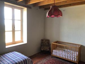 ein Schlafzimmer mit einem Kinderbett und einem Fenster in der Unterkunft Le Tarde - Crécerelle in Saint-Désiré
