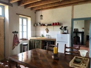 a kitchen with a wooden table and a white refrigerator at Le Tarde - Crécerelle in Saint-Désiré