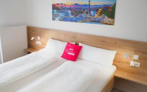 1 dormitorio con cama blanca y almohada roja en Kummers Motel en Völkermarkt