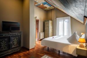 a bedroom with a large white bed and a television at Hotel La Casueña in Lanuza