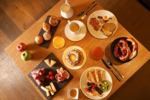 uma mesa de madeira com pratos para o pequeno-almoço em HANNONG Hotel & Wine Bar em Estrasburgo