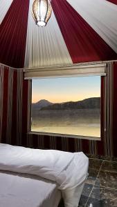 a bed in a tent with a large window at Bright stars rum camp in Wadi Rum