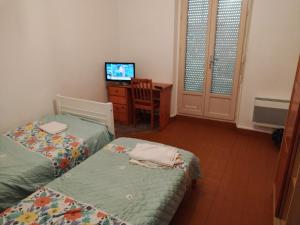 a room with two beds and a desk with a television at LOUE MAISON ENTIÈRE PROPRE ! , Endroit calme, à 5 minutes gare mantes la jolie, in Mantes-la-Jolie