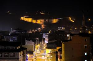 Kars Konak Hotel في كارس: اطلالة على مدينة في الليل مع قلعة