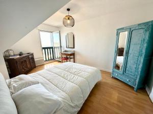 een slaapkamer met een groot bed en een blauwe spiegel bij EXCEPTIONNEL ! T3 Duplex – Vue mer 180° sur le port de Lomener in Ploemeur