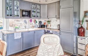 a kitchen with blue cabinets and a white chair at Cozy Home In Egersund With Wifi in Egersund