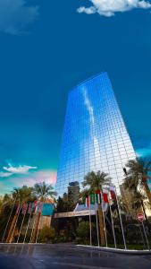 AlHamra Hotel Kuwait في الكويت: مبنى عاكس طويل مع أشجار النخيل أمامه