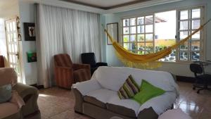 uma sala de estar com um sofá e uma rede de descanso em Diversão, churrasco e piscina - Praia de Ipitanga em Salvador