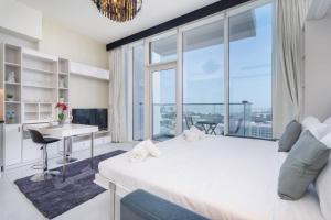 1 dormitorio con cama, escritorio y ventana grande en Lovely Studio with View of Dubai Miracle Garden en Dubái