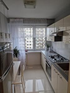 uma cozinha branca com um fogão e uma janela em APARTAMENT - 2 pokoje w Łodzi - blisko Atlas Arena, Zoo, Centrum, Piotrkowska em Lódź