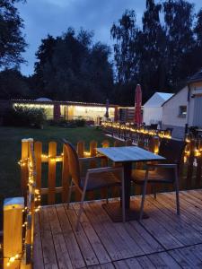 una terrazza in legno con tavolo, sedie e luci di Glamping UNIVERSE a Ettelgem