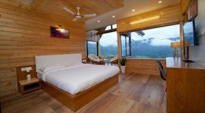 a bedroom with a bed and a large window at Vrindhavan Farm Suites in Kanthalloor