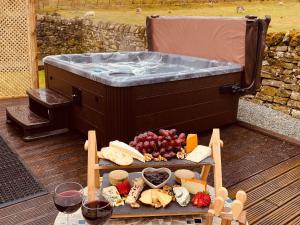 een hot tub met een dienblad met kaas en fruit bij Lily Rose Cottage in Gilsland