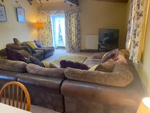 a living room with a large brown leather couch at Lily Rose Cottage in Gilsland