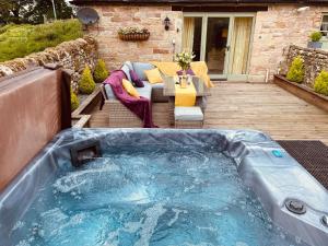 een hot tub in het midden van een patio met een tafel bij Lily Rose Cottage in Gilsland