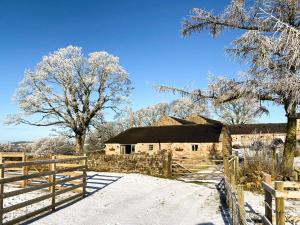 een oude schuur in de sneeuw met een houten hek bij Lily Rose Cottage in Gilsland