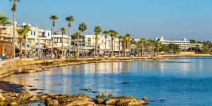 a body of water with palm trees and buildings at Queens Gardens suite by the sea, pool and mall in Nea Paphos