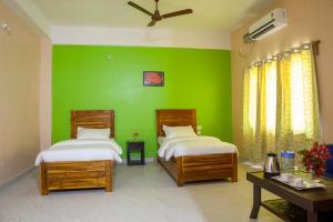 a green room with two beds and a green wall at Rains Inn Eco Hotel in Diphu +16 photos