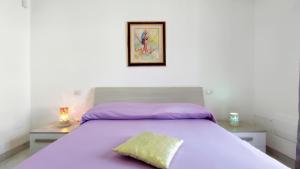 1 dormitorio con cama morada y almohada amarilla en Le Sorelle del Mare - Sole e Persia, en Marina di Pescoluse