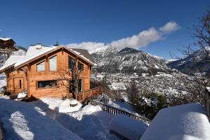 uma casa de madeira na neve com uma montanha em CHALET SERRE CHEVALIER AVEC VUE EXCEPTIONNELLE em Puy-Saint-Pierre