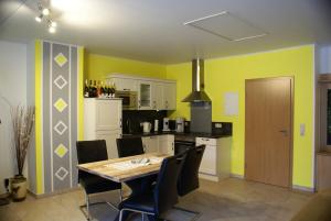 une cuisine avec des murs jaunes, une table et des chaises dans l'établissement Beilsteiner Ferienwohnungen, à Beilstein