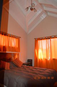 1 dormitorio con 1 cama con cortina naranja en Cerro Negro, Complejo en Villa General Belgrano