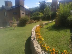 una pared de retención junto a un patio con flores en Cerro Negro, Complejo en Villa General Belgrano