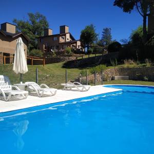 una piscina con 2 sillas y una sombrilla en Cerro Negro, Complejo en Villa General Belgrano