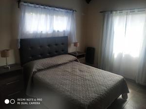 1 dormitorio con 1 cama y 2 ventanas en Cerro Negro, Complejo en Villa General Belgrano