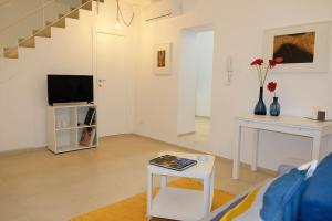 een witte woonkamer met een tv en een tafel bij Dimora d'Artista in Ragusa