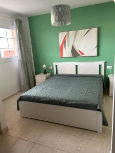 - une chambre avec un lit et un mur vert dans l'établissement Il Paradiso Esiste, à Costa Calma