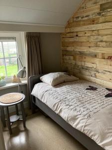 a bedroom with a bed with a wooden wall at bed en breakfast westerwolde in Sellingen