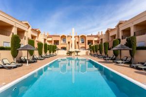 a pool in the courtyard of a hotel with chairs and umbrellas at Baia da Luz - Tropicana Beach Apartment in Luz
