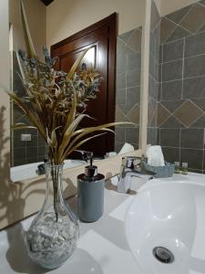 a vase of flowers sitting on a bathroom sink at L' Antica Trebbia - Rooms in Caltanissetta