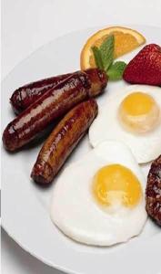 a plate of food with sausage and eggs and strawberries at Nite Inn Bed & Breakfast in Leeds