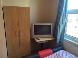 a bedroom with a tv and a desk with a bed at Nite Inn Bed & Breakfast in Leeds