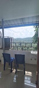 a room with two chairs and a balcony with a view at Hotel Greenvalley Residency in Punalūr
