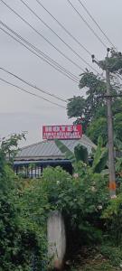 a building with a sign in the background with plants at Hotel Greenvalley Residency in Punalūr