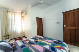 a bedroom with a bed with a colorful comforter at Melvis' place in Dar es Salaam