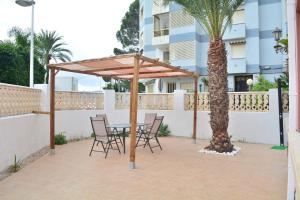 drewniana pergola z krzesłami, stołem i palmą w obiekcie CHALET VILLA Los HIPOCAMPOS w mieście Cullera