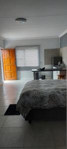 a bedroom with a bed and a desk and a kitchen at TJ Self-catering in Graaff-Reinet