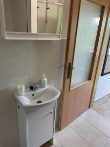 baño con lavabo, espejo y puerta en Apartmán KATARINA v Penzióne pod Smrekom en Martin