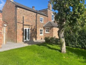 um edifício de tijolos com uma árvore em frente em The Annex: 2 bedroom cottage, countryside, peaceful getaway with garden em Easingwold