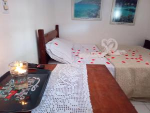 a room with two beds and a table with a candle at Suite Ilha Grande in Angra dos Reis