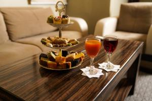 uma mesa com uma bandeja de comida e dois copos de vinho em La Rive Hotels & Suites em Dammam
