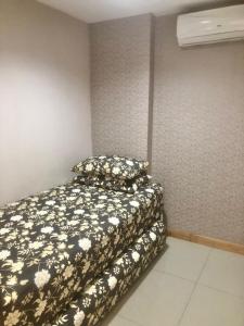 um quarto com uma cama com um cobertor preto e branco em Apartemen Ciumbuleuit 2 em Bandung