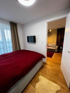 a bedroom with a red bed and a living room at Apartman Carra in Jahorina