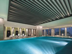 a swimming pool in a hotel with chairs and tables at New World Beijing Hotel in Beijing