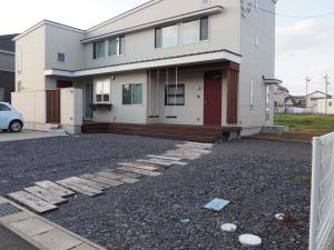 a house with a gravel driveway in front of it at MARBLE B&B in Kashima