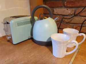 a tea kettle and two cups on a table at Happy Stay in Gliwice